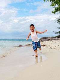 Full length of woman standing at beach against sky