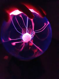 Close-up of hand holding illuminated light against black background