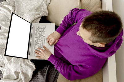 Man relaxing on bed and holding laptop computer. mock up with blank white screen. man using notebook