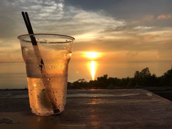 Close-up of drink on table against sunset