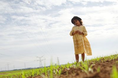 Portrait of girl standing on farm field against sky