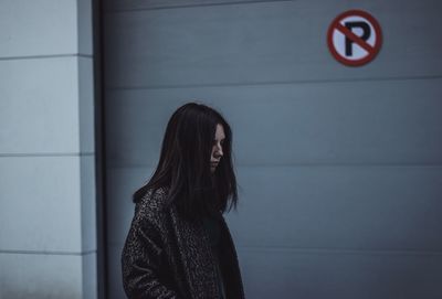 Side view of woman standing against wall