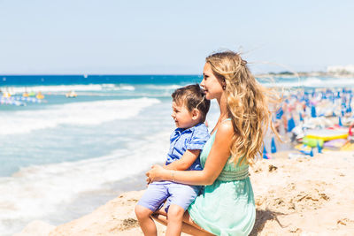 Happy friends enjoying at beach against sea