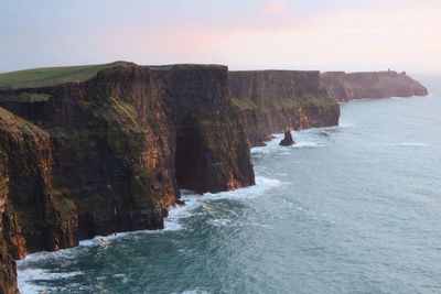 Scenic view of cliff by sea against sky