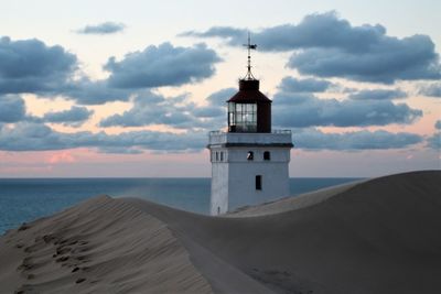 Lighthouse on beach against sky