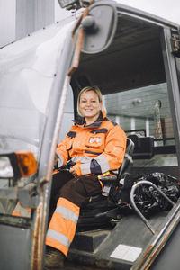 Full length of female construction worker sitting in vehicle