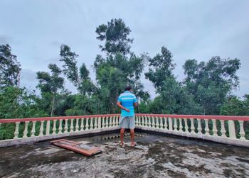 Rear view of man standing by bridge against sky