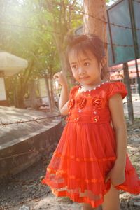 Cute girl looking away while standing by fence