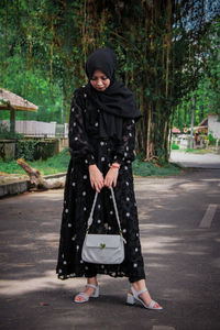 Portrait of woman standing against trees