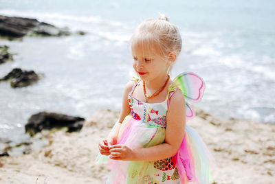 Portrait of cute girl in butterfly costume standing at beach