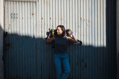 Young woman standing by corrugated iron