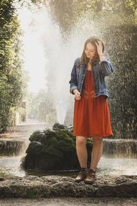 Full length of woman standing on rock against fountain
