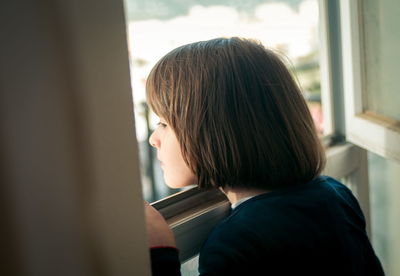 Portrait of boy looking through window at home