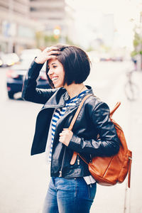 Side view of young woman standing on road in city