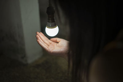 Close-up of woman hand under light bulb at home