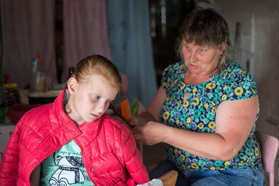 A woman braids a braid to a girl at the dacha and lectures her