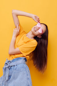 Midsection of young woman with long hair against yellow background