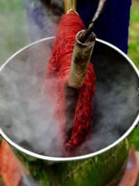 Close-up of red fabric hanging over container emitting steam