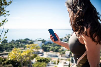 Girl looking at the mobile with the sea in the background