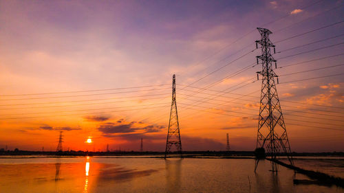 Silhouette electricity pylon against sky during sunset