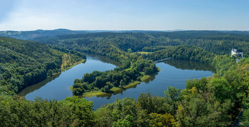 High angle view of river bend with green trees against sky