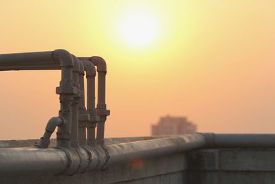 Close-up of pipes on building terrace against sky during sunset