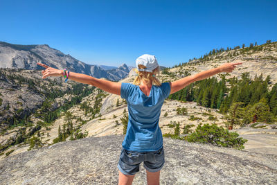 Rear view of woman standing on mountain against sky