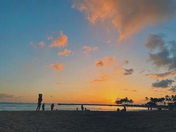 Silhouette people on beach against sky during sunset