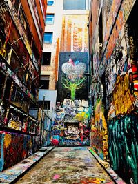 Graffiti on narrow alley amidst buildings in city