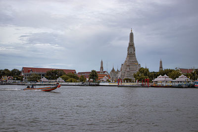 View of buildings at waterfront against cloudy sky