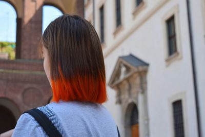 Woman with dyed hair standing against building