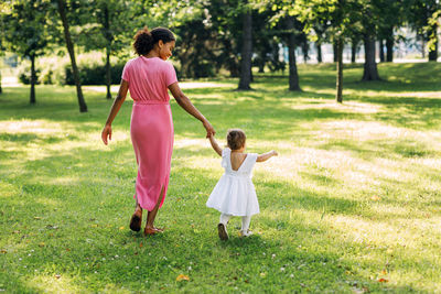 Full length of mother and girl standing on grass