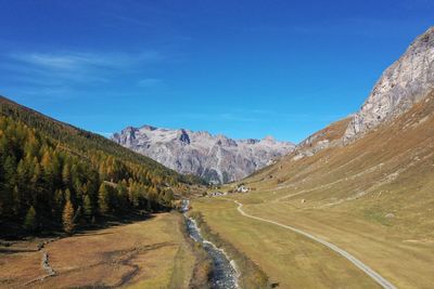 Scenic view of road by mountains against blue sky