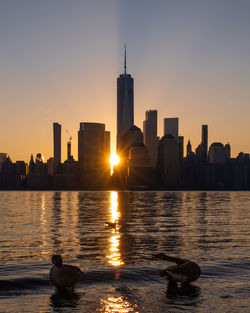 Scenic view of river and buildings against sky during sunset
