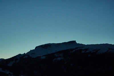 Low angle view of snowcapped mountain against clear blue sky