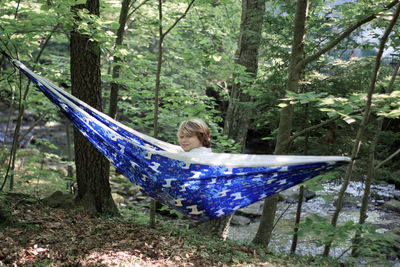 Woman sitting on hammock in forest