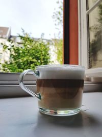 Close-up of coffee cup on window sill