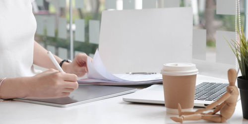 Midsection of woman holding coffee cup on table