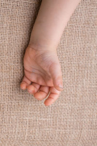 Cropped hand of baby on jute