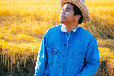 Young man looking away while standing on land