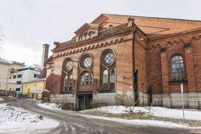 Low angle view of snow covered building against sky