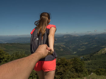 Rear view of woman with arms raised against sky