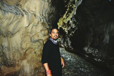 Portrait of man standing against rock formation