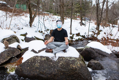 Full length of young man sitting on rock