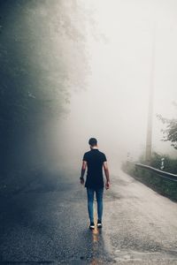 Full length rear view of man walking on road