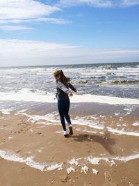 Woman standing on beach against sky