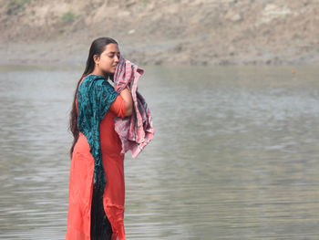 Side view of young woman standing in lake