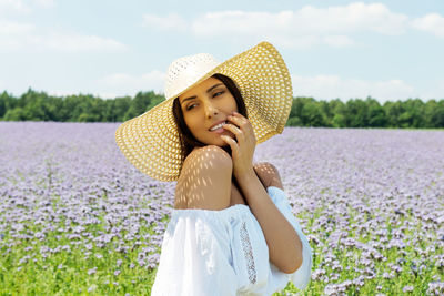 Thoughtful beautiful woman wearing hat while standing on field