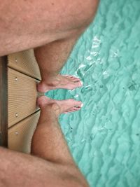 Low section of man relaxing in swimming pool