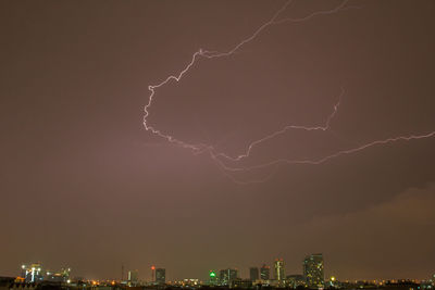 Low angle view of lightning over illuminated buildings in city